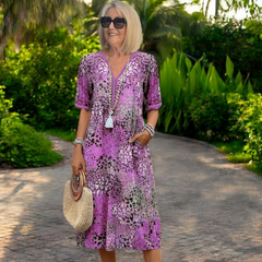 Vestido de primavera Karolína de longitud media de Warszawska Elegancja sobre fondo lila y paisaje isleño.